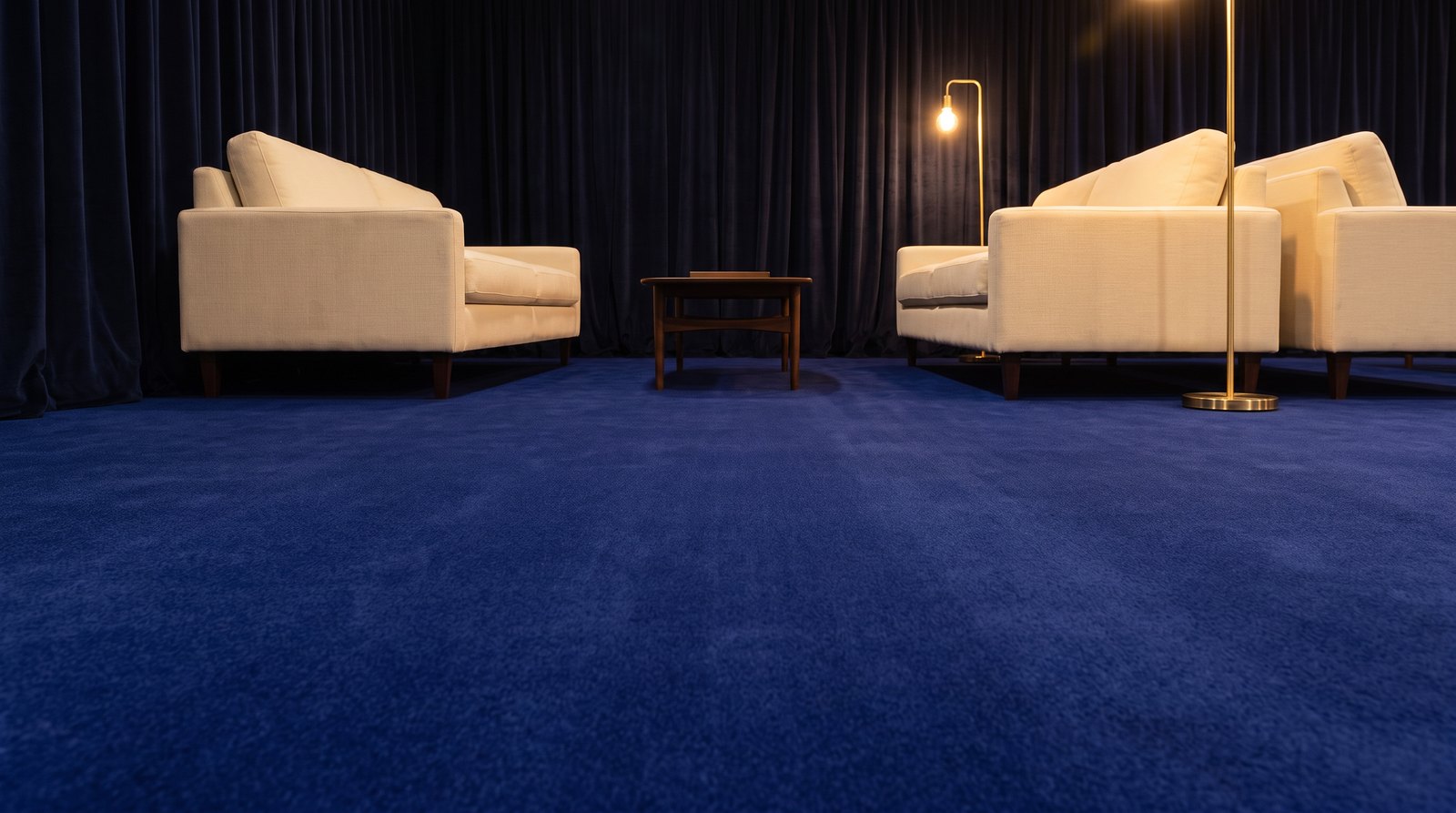 Deep navy velour event carpet in a warm-lit VIP lounge with cream sofas