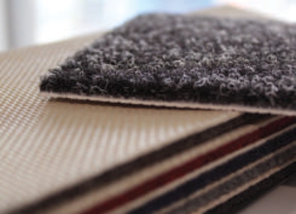 Edge of stacked gym floor cover tiles showing the textile face and backing