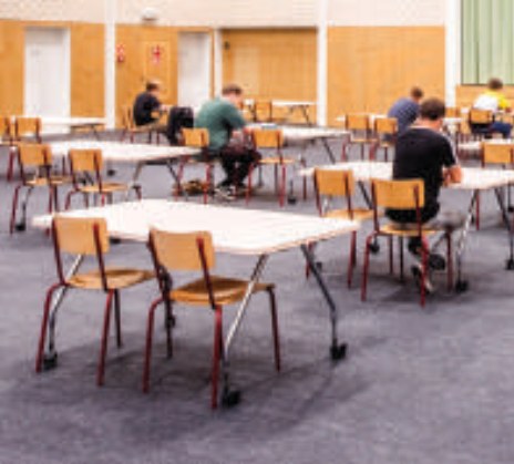 Gym floor covered in grey cover tiles with rows of exam tables and chairs
