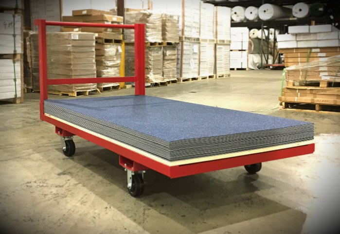 Red rolling storage cart loaded with a stack of blue gym floor cover tiles